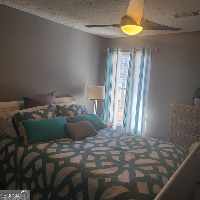 bedroom with ceiling fan and a textured ceiling