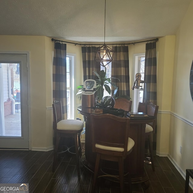 dining space with bar area, a textured ceiling, and dark hardwood / wood-style floors