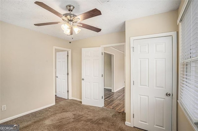 unfurnished bedroom featuring a textured ceiling, dark carpet, and ceiling fan