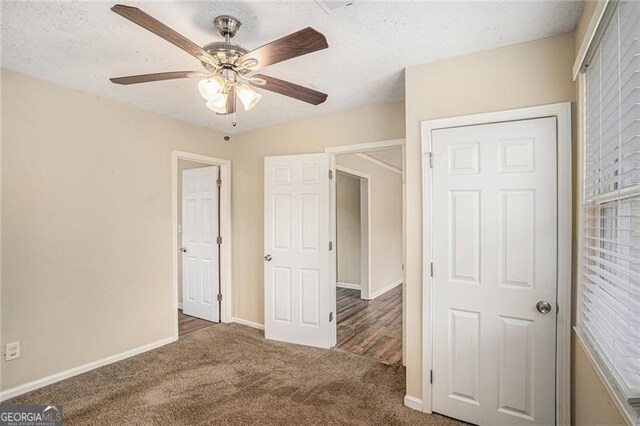 unfurnished bedroom with ceiling fan, dark carpet, and a textured ceiling