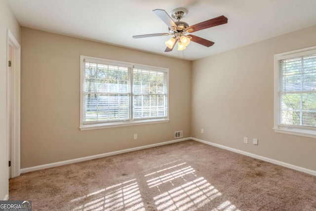 empty room with ceiling fan, plenty of natural light, and light colored carpet