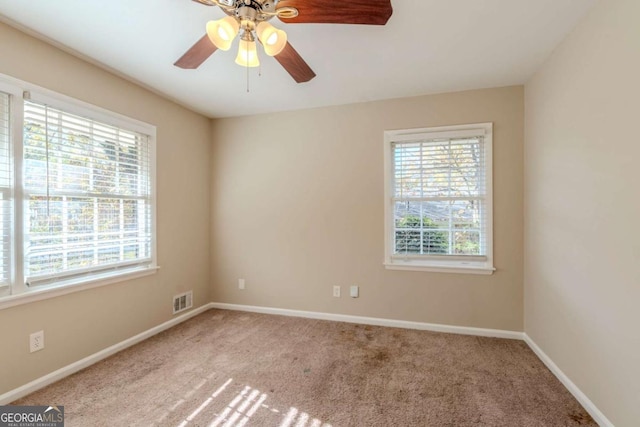 spare room featuring a wealth of natural light, ceiling fan, and light colored carpet