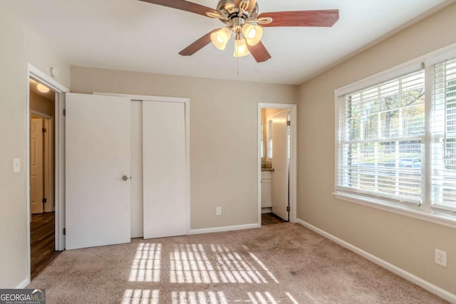 unfurnished bedroom featuring connected bathroom, ceiling fan, a closet, and light colored carpet