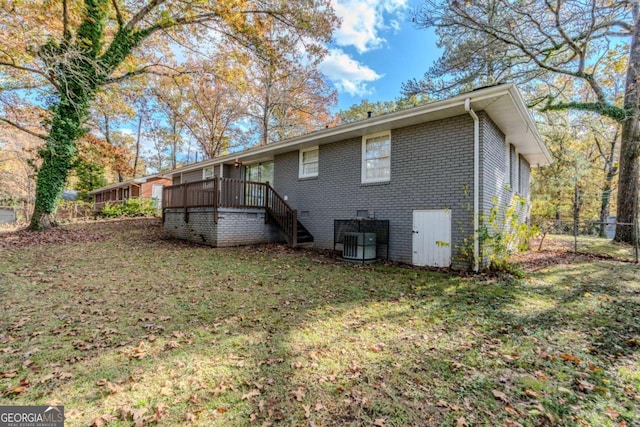 rear view of house featuring a lawn, central AC, and a deck