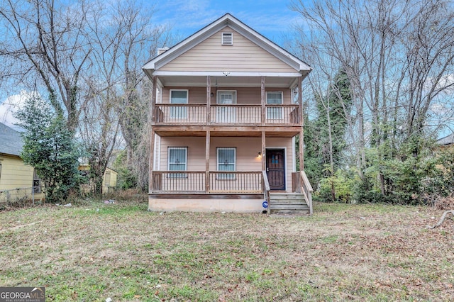 view of property with a balcony and a front lawn