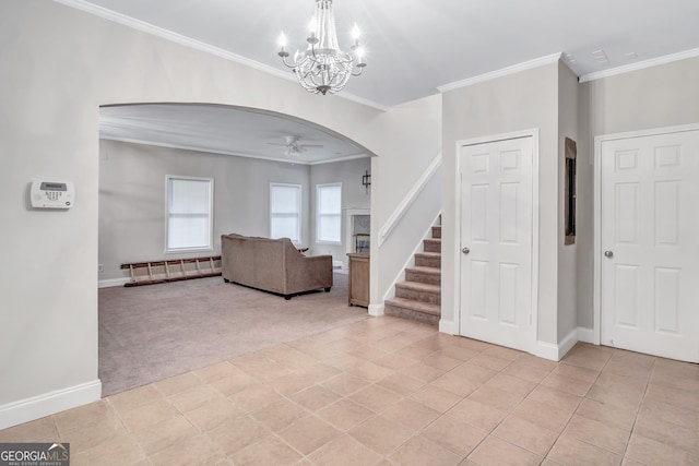 carpeted entrance foyer featuring crown molding and ceiling fan with notable chandelier