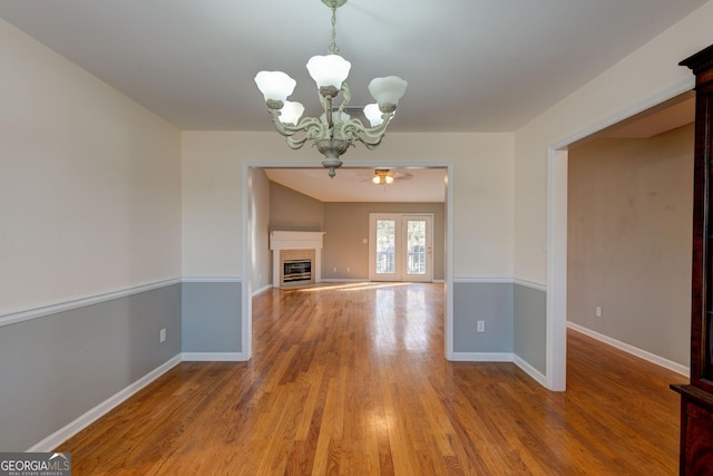 unfurnished dining area featuring ceiling fan with notable chandelier and hardwood / wood-style flooring