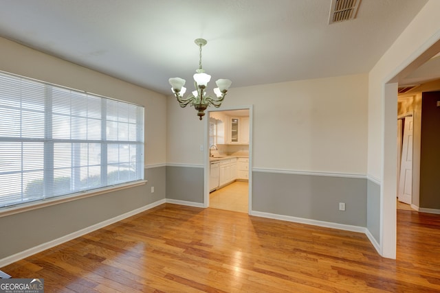 spare room with a chandelier, sink, and light hardwood / wood-style flooring