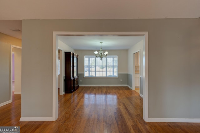 unfurnished dining area featuring wood-type flooring and an inviting chandelier