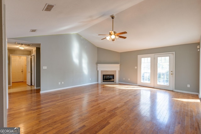 unfurnished living room featuring a fireplace, light wood-type flooring, ceiling fan, and lofted ceiling