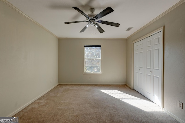 unfurnished bedroom featuring ceiling fan, light colored carpet, ornamental molding, and a closet