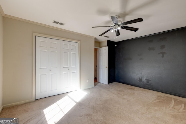 unfurnished bedroom featuring a closet, ceiling fan, ornamental molding, and light colored carpet