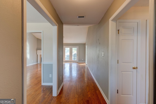 corridor with french doors and hardwood / wood-style flooring