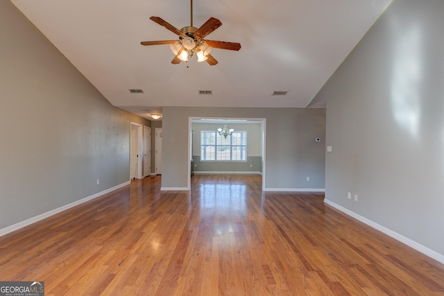 unfurnished living room with ceiling fan with notable chandelier and hardwood / wood-style flooring