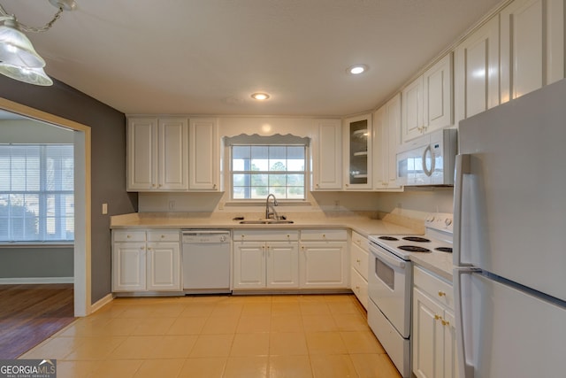 kitchen with white cabinets, white appliances, sink, and light hardwood / wood-style flooring