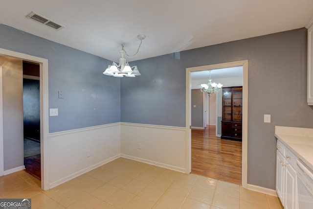 unfurnished dining area with light hardwood / wood-style floors and a notable chandelier