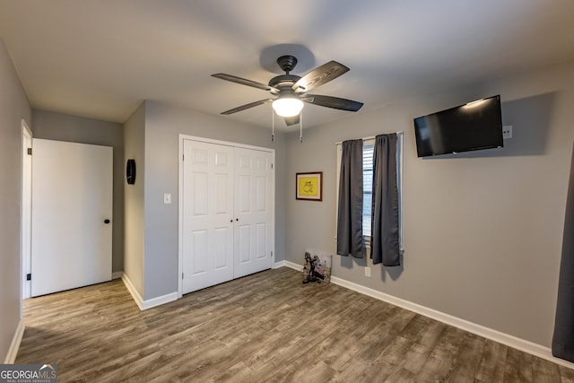 unfurnished bedroom with ceiling fan, hardwood / wood-style floors, and a closet