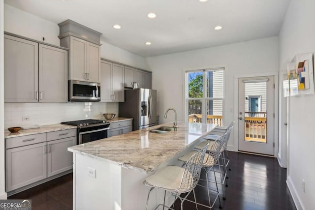 kitchen with gray cabinetry, light stone countertops, sink, and appliances with stainless steel finishes