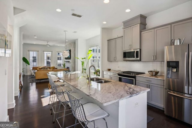 kitchen with a center island with sink, gray cabinets, and stainless steel appliances