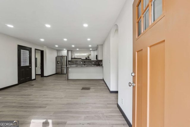 kitchen with kitchen peninsula, white cabinetry, light hardwood / wood-style floors, and stainless steel refrigerator with ice dispenser