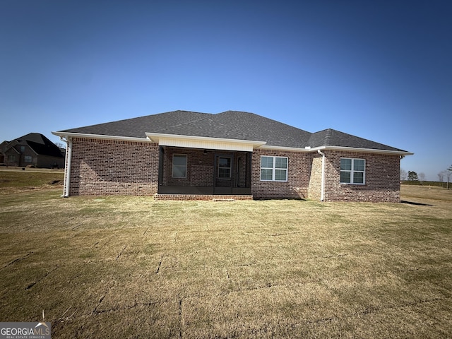 back of property with brick siding and a lawn