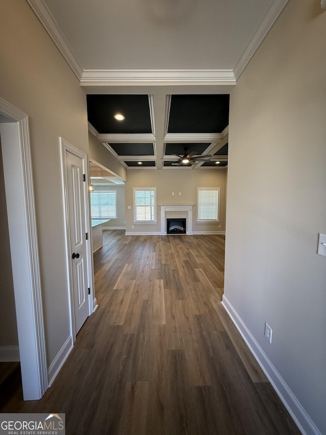 hallway with dark wood-type flooring, coffered ceiling, baseboards, beam ceiling, and crown molding