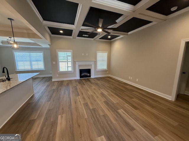 unfurnished living room with a fireplace, dark wood-type flooring, a sink, coffered ceiling, and baseboards