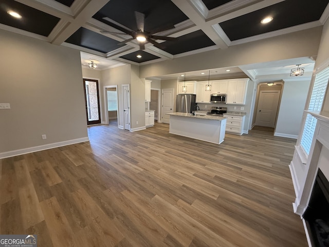 kitchen with an island with sink, appliances with stainless steel finishes, open floor plan, hanging light fixtures, and white cabinetry