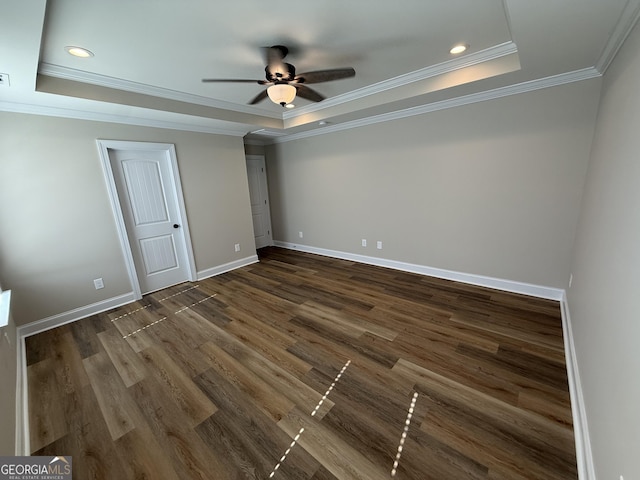 unfurnished bedroom with dark wood-style floors, a tray ceiling, ornamental molding, and baseboards