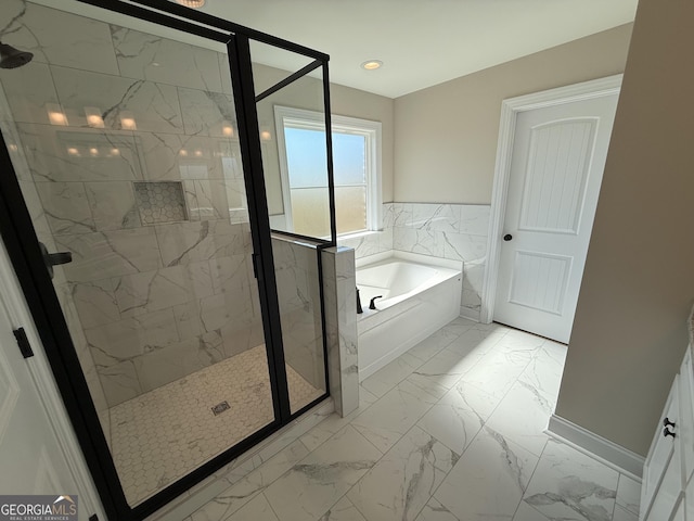 full bathroom featuring baseboards, marble finish floor, a garden tub, and a shower stall