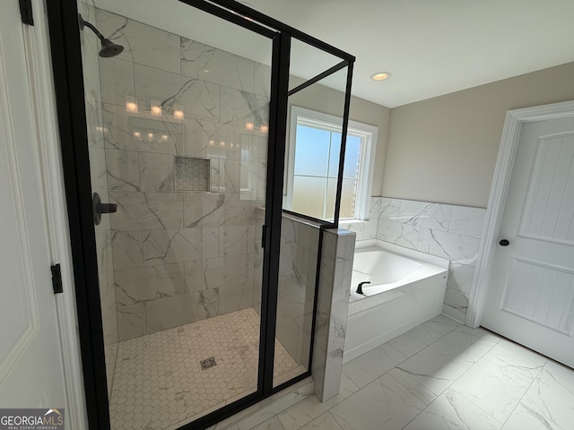 bathroom featuring marble finish floor, a garden tub, tile walls, and a shower stall