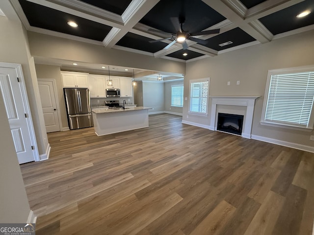 kitchen featuring white cabinets, appliances with stainless steel finishes, open floor plan, and decorative light fixtures