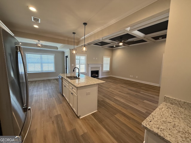 kitchen featuring light stone counters, pendant lighting, stainless steel appliances, white cabinets, and a sink