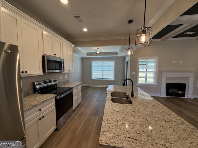 kitchen with open floor plan, stainless steel appliances, a sink, and white cabinets