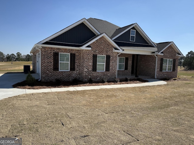 view of front facade featuring brick siding, board and batten siding, and a front lawn