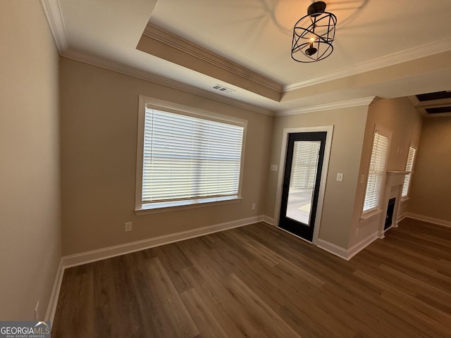 entrance foyer with crown molding, a raised ceiling, dark wood finished floors, and baseboards