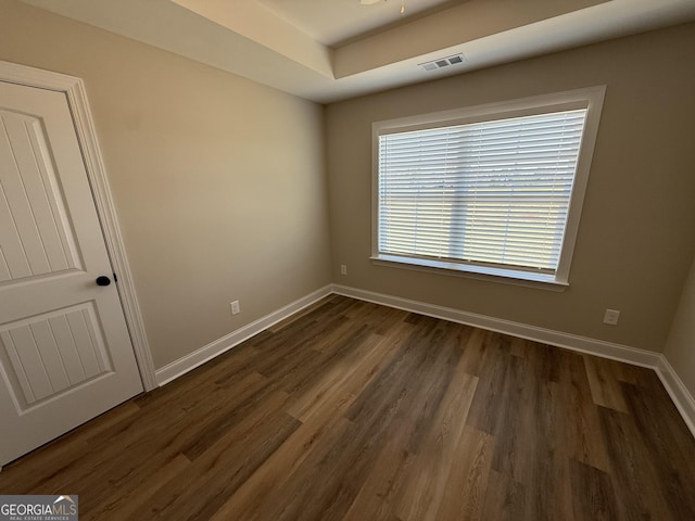 unfurnished bedroom featuring dark wood-style flooring, visible vents, and baseboards