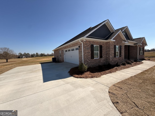 view of side of home featuring brick siding, board and batten siding, a garage, cooling unit, and driveway