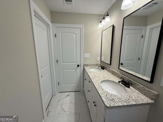 bathroom featuring marble finish floor, visible vents, a sink, and double vanity