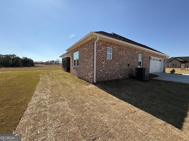 view of home's exterior featuring a garage, central AC, brick siding, driveway, and a lawn