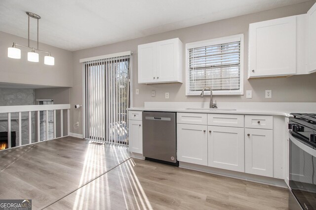 kitchen featuring a high end fireplace, dishwasher, white cabinets, and pendant lighting