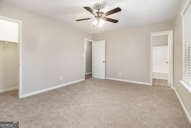 unfurnished bedroom featuring ceiling fan, light carpet, and ensuite bath