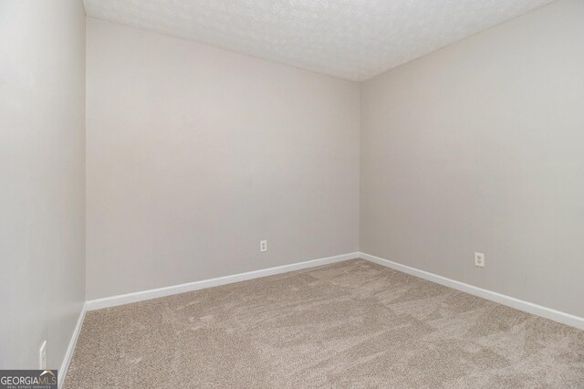 unfurnished room featuring a textured ceiling and light carpet