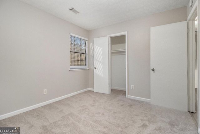 unfurnished bedroom with a textured ceiling, light carpet, and a closet