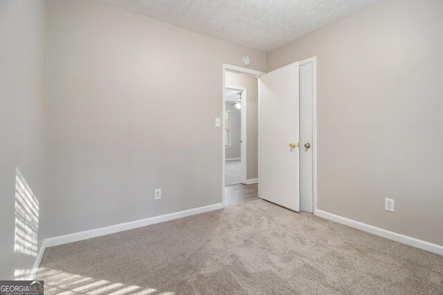 carpeted spare room with ceiling fan and a textured ceiling