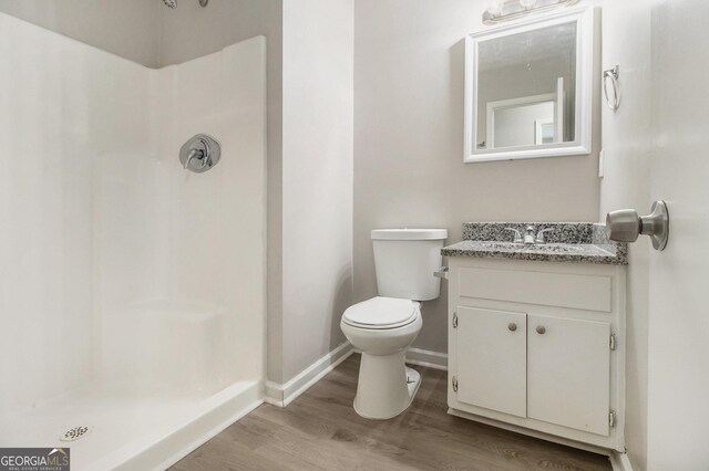 bathroom with hardwood / wood-style floors, vanity, toilet, and a shower