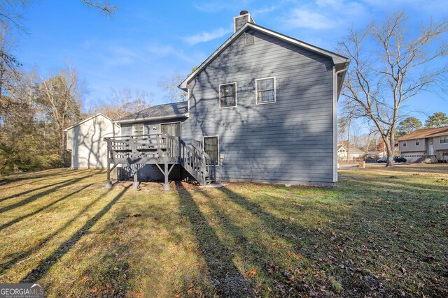 rear view of house with a wooden deck and a yard