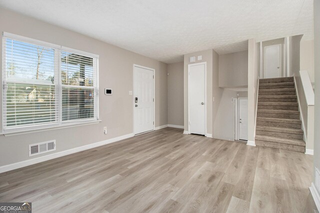 unfurnished living room featuring a textured ceiling and light hardwood / wood-style flooring