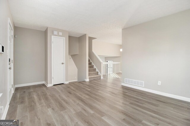 unfurnished living room featuring light hardwood / wood-style floors and a textured ceiling