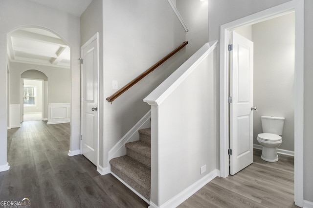 staircase with beam ceiling, coffered ceiling, and hardwood / wood-style floors